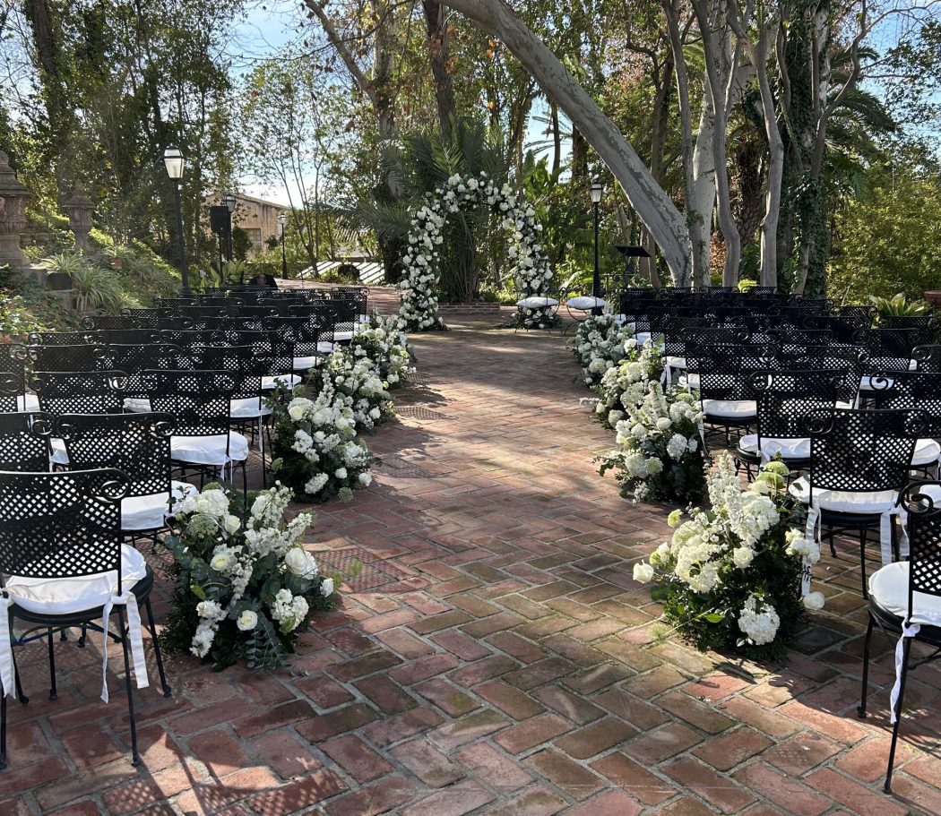 White Fields Ceremonia al aire libre con sillas negras y decoraciones florales blancas.
